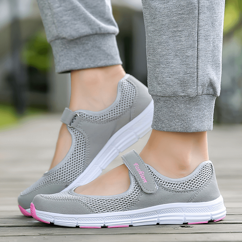 Gray women's breathable vulcanized flat shoes with mesh design and hook and loop closure, worn outdoors.